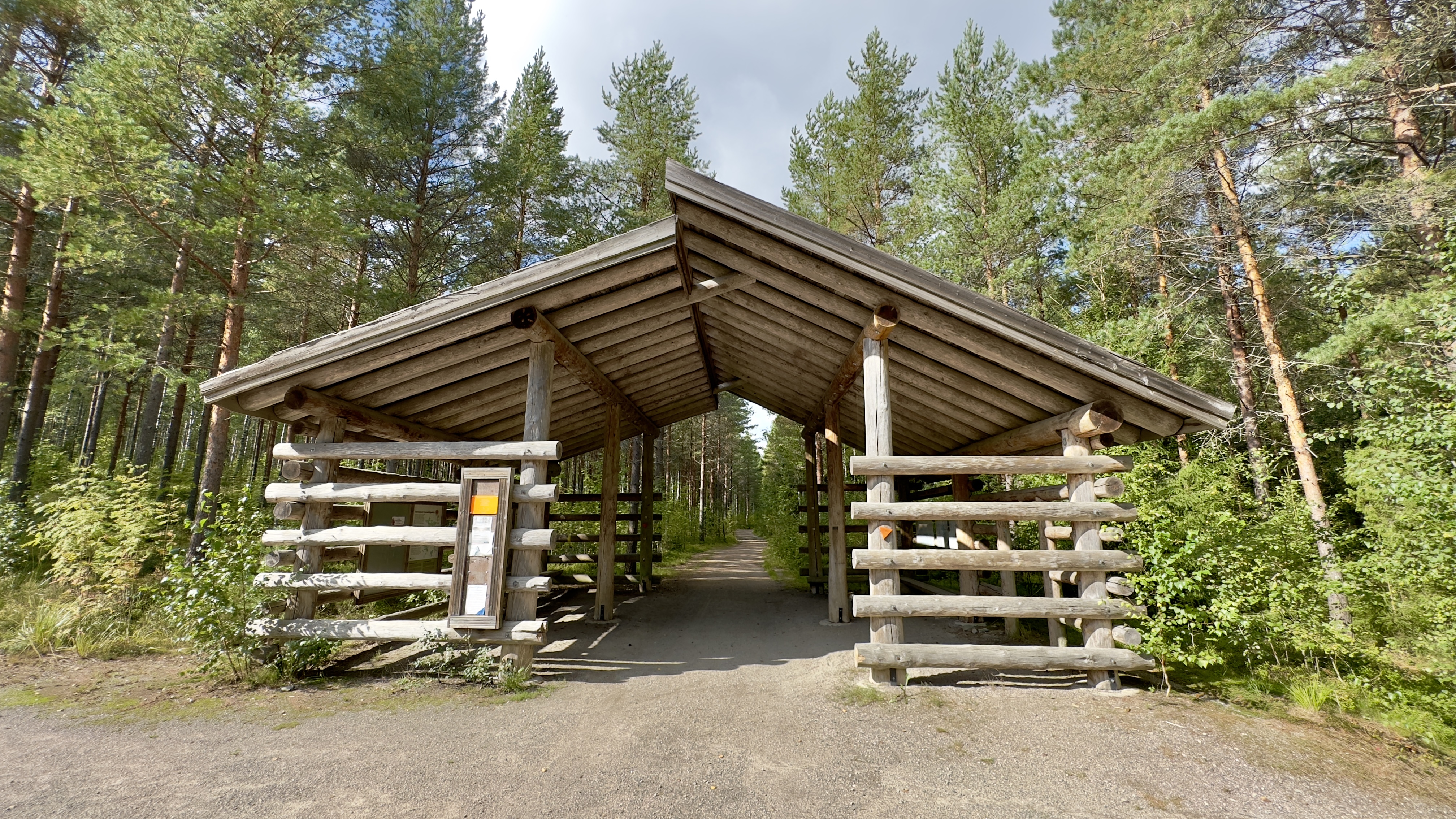There is a large wooden gate in the forest with a large canopy over it.