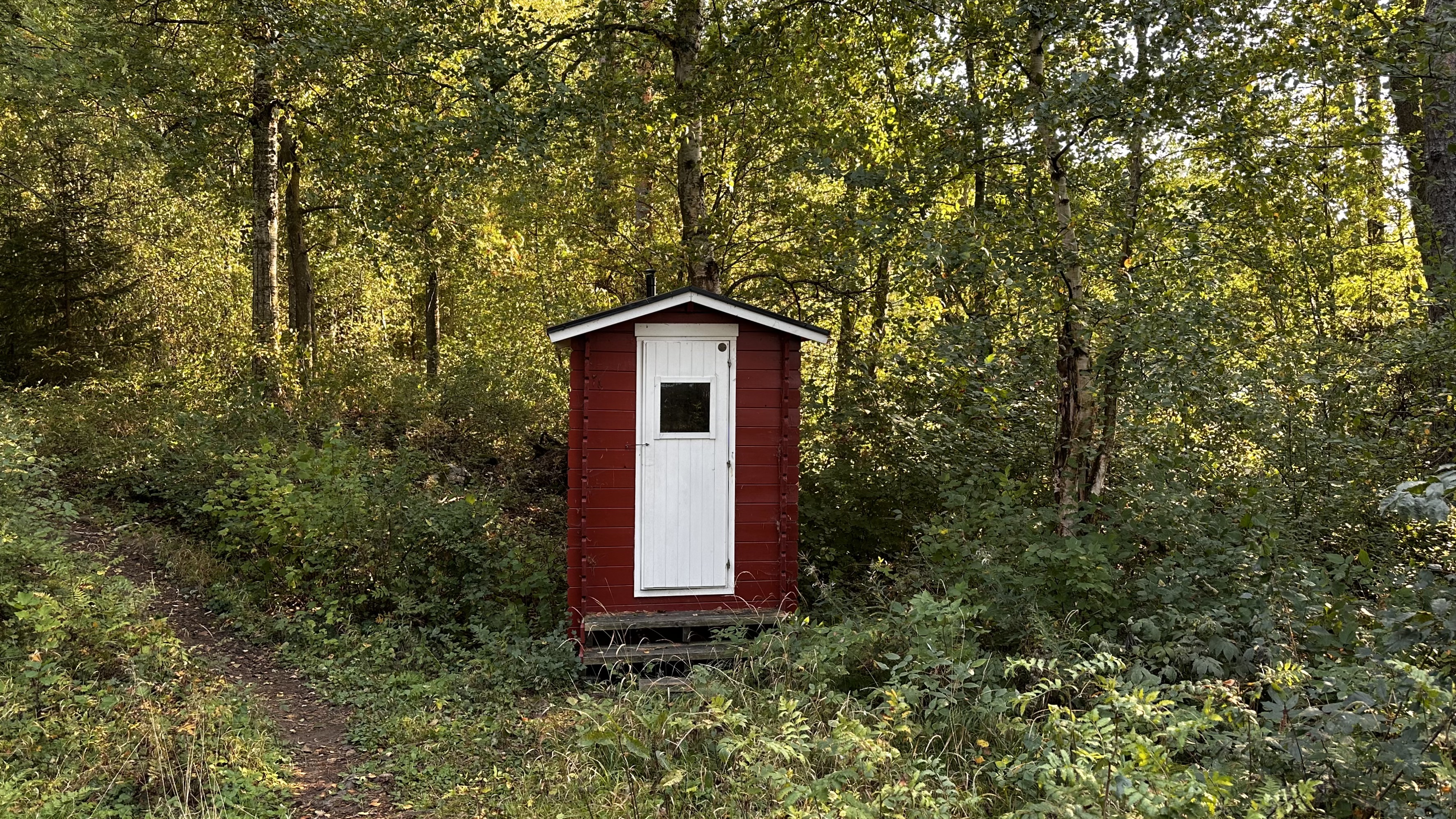 Punainen kuivakäymälä, jossa valkoinen ovi.