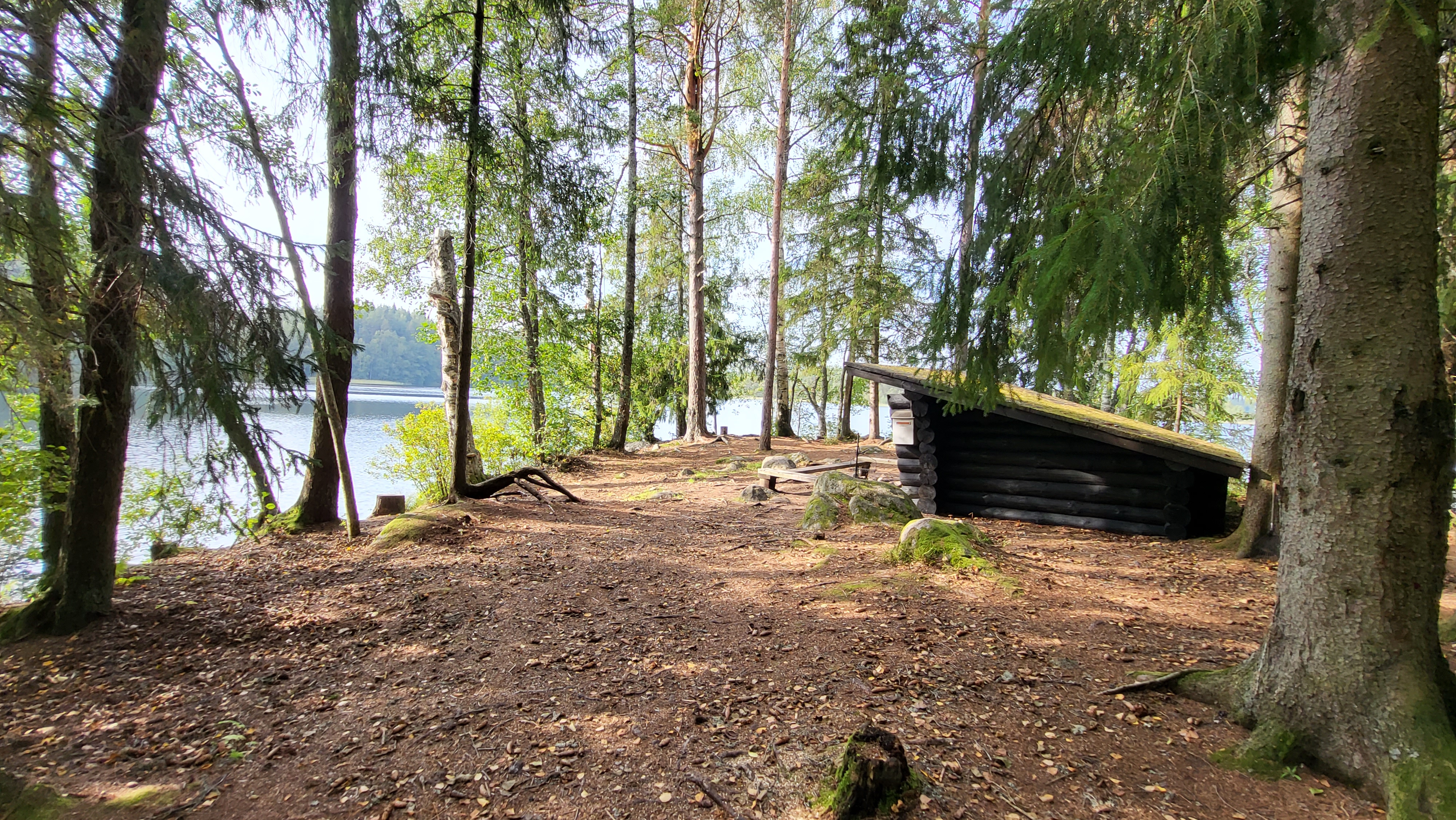 Laavun edessä on pieni nuotiokehä ja eteen avautuu järvimaisema.