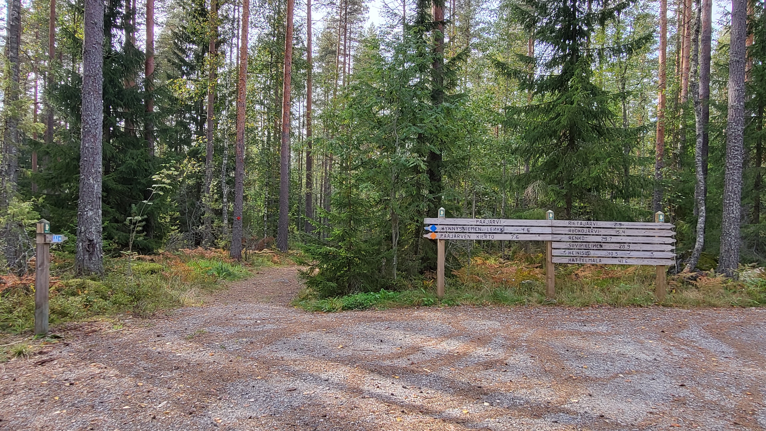 Kyltti metsän laidalla hiekkapohjaisella alueella.