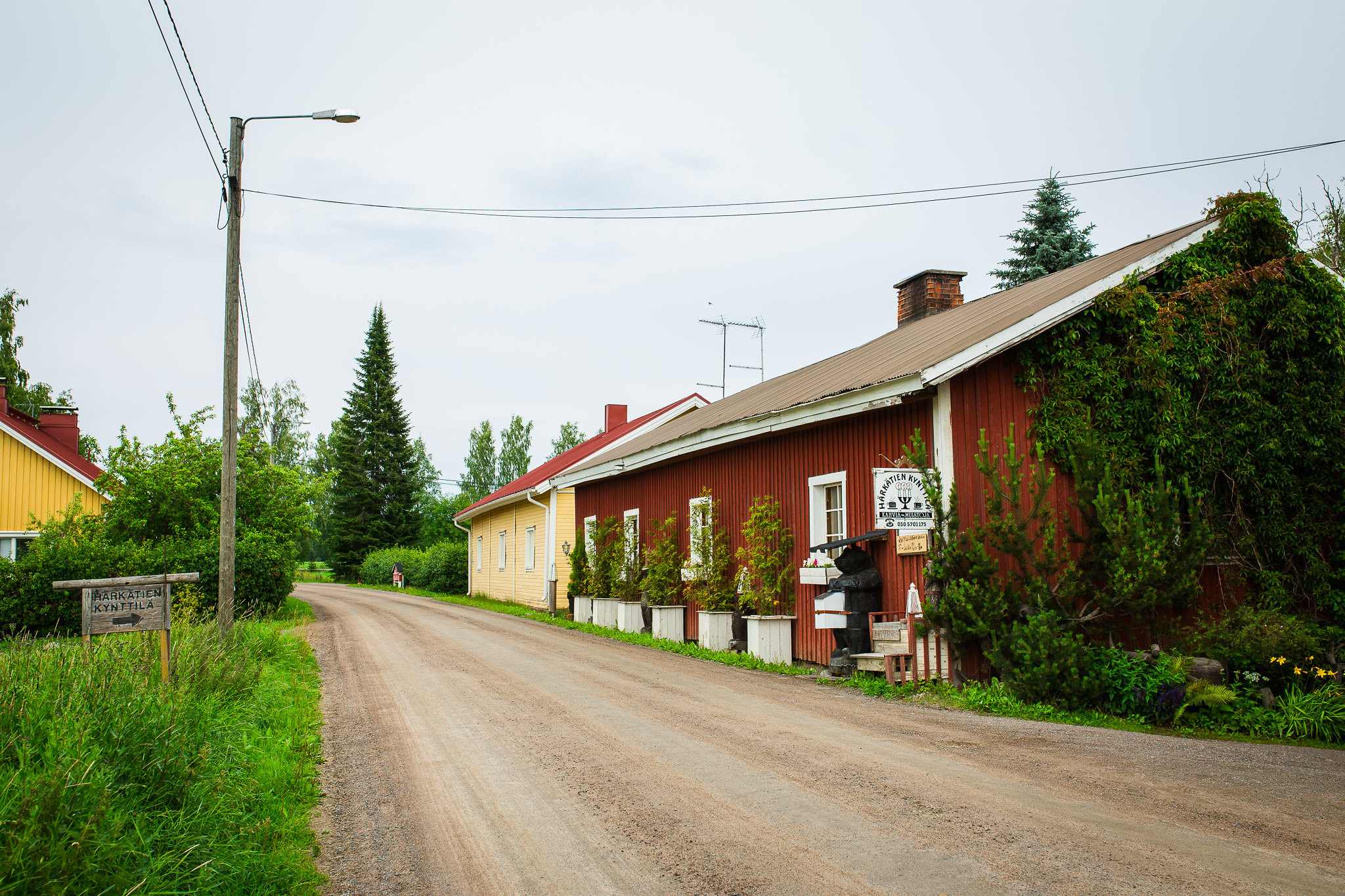 Red wooden house next to a gravel road.