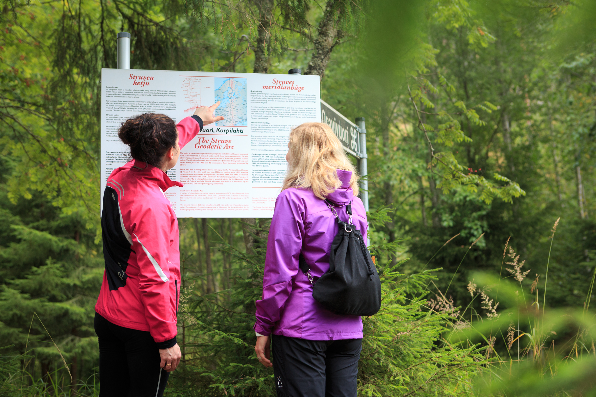 Two people examining the Oravivuori nature tail information board