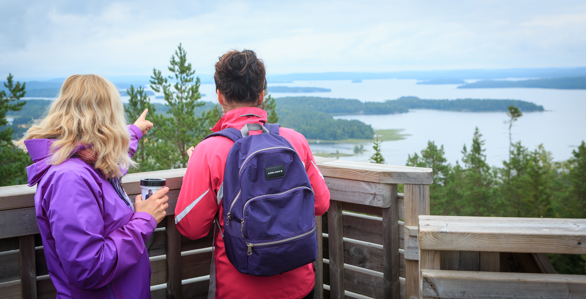 Two people standing in a look-out tower watching the lake view beyond.