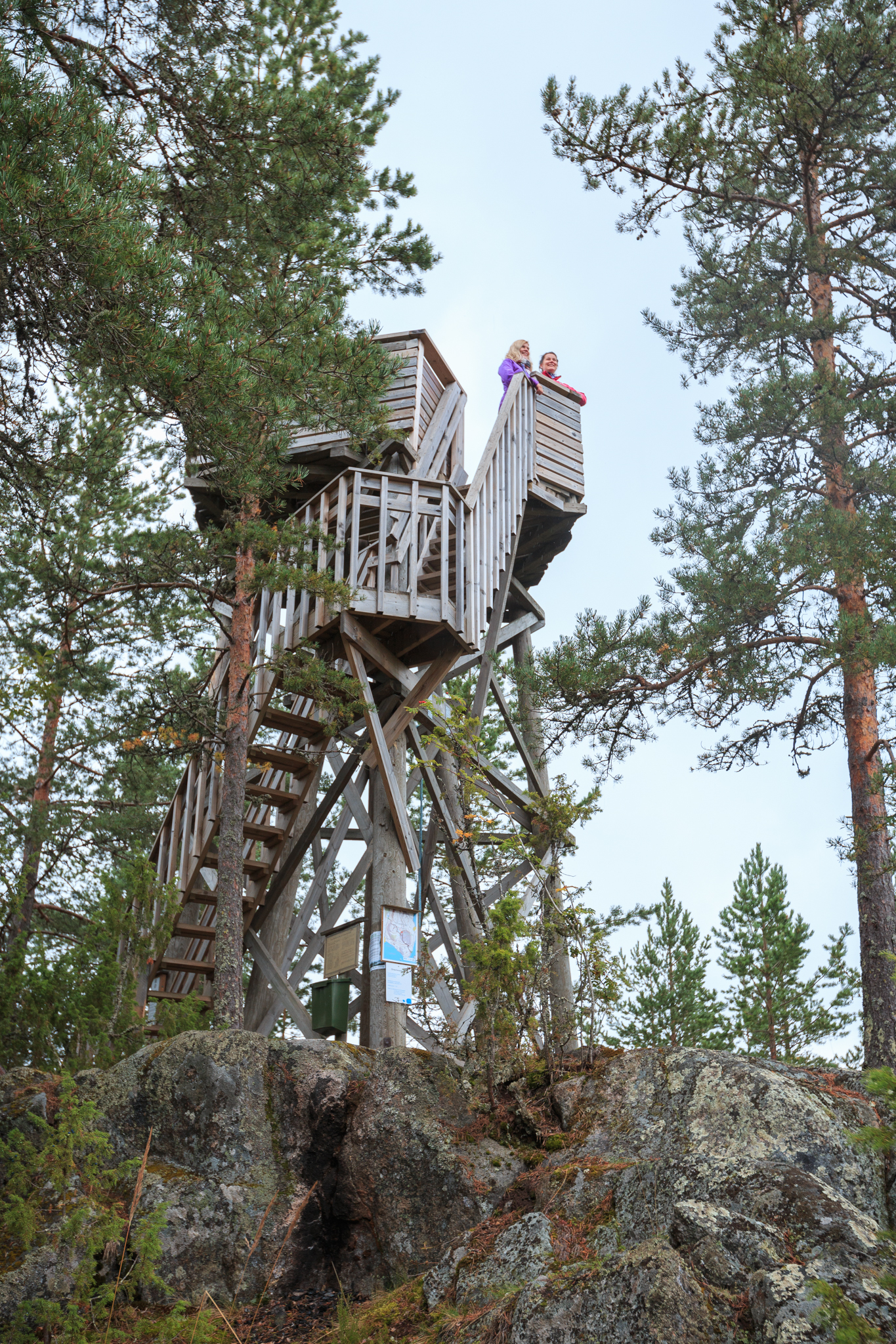 Two people at the top of the Oravivuori Triangluation tower. Photographed from below so the whole tower is in view.