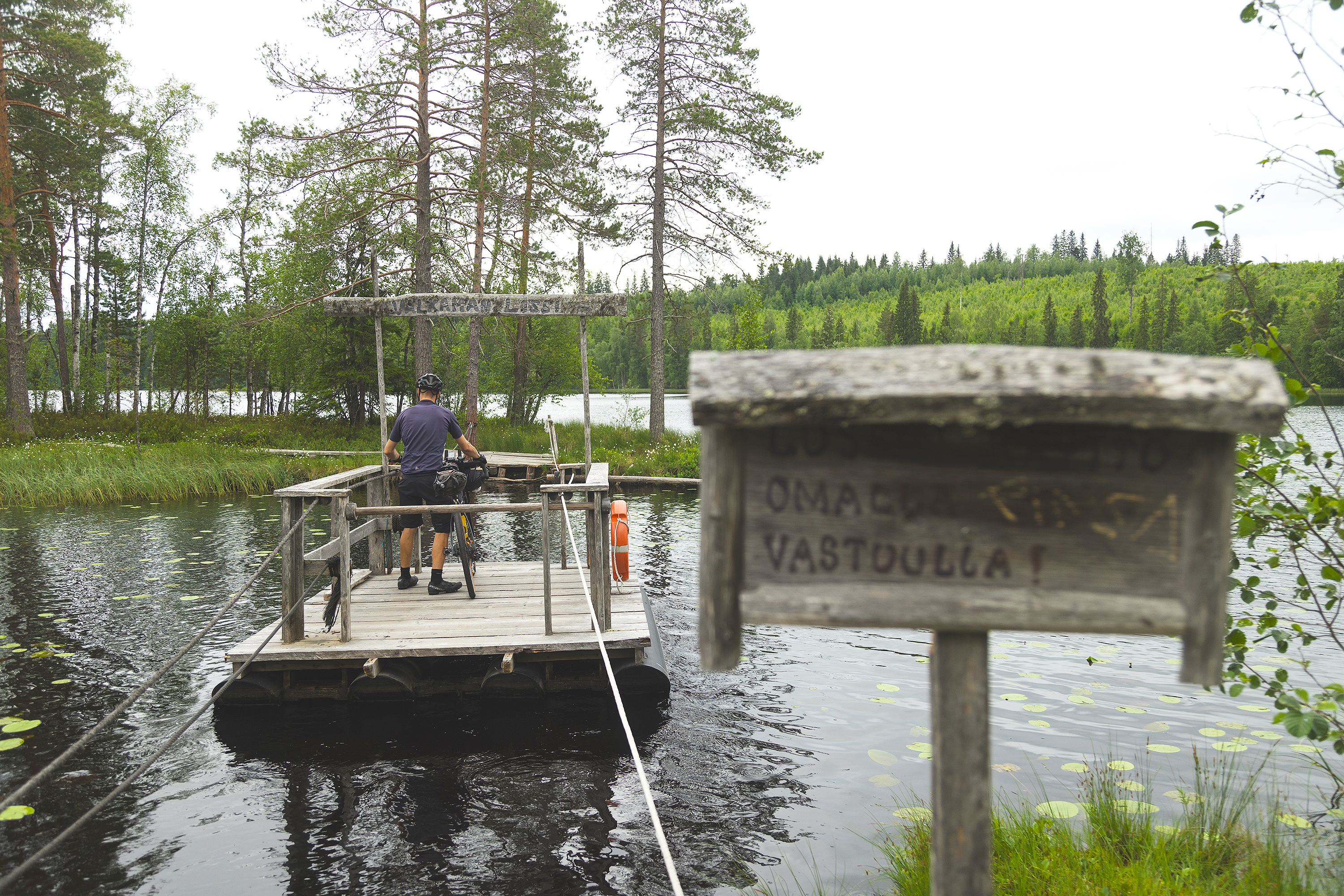 A person and bike taking a rope ferry to a small island.