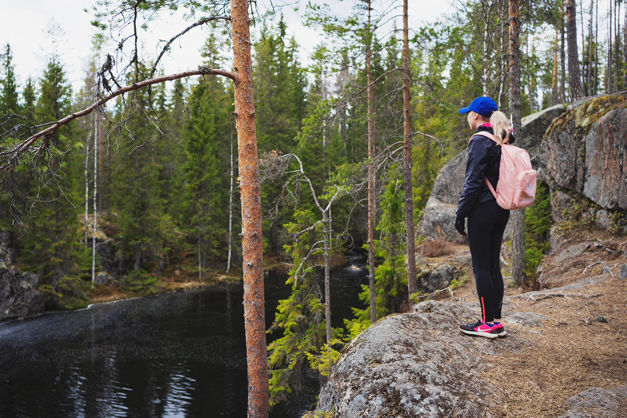 Henkilö katsomassa rotkojärveä kallion laelta