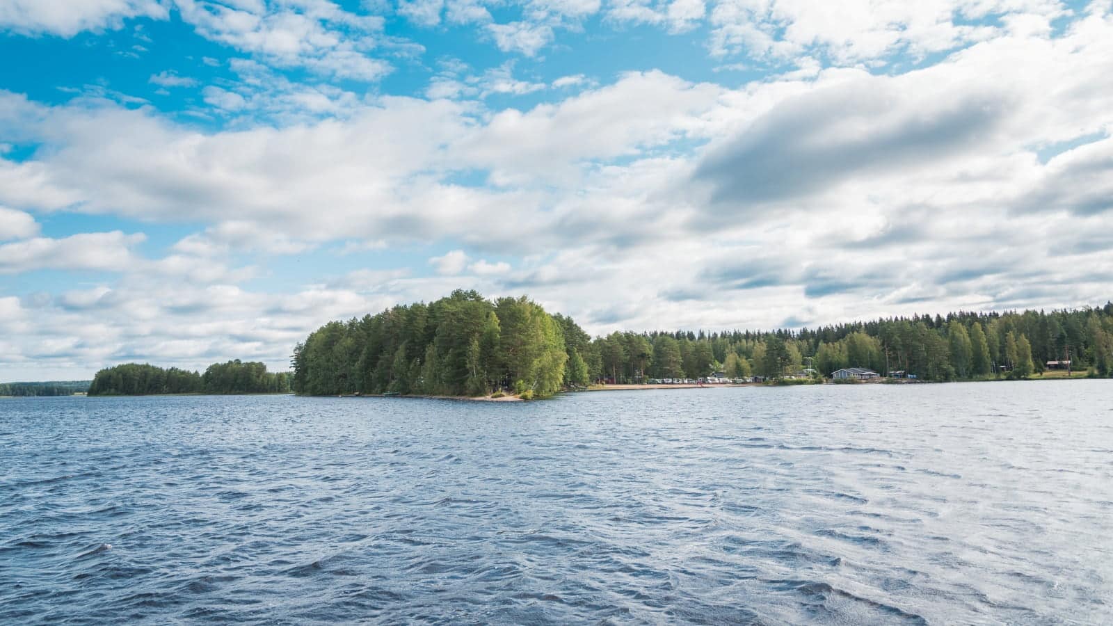 Kesäinen järvimaisema, jonka keskellä näkyvissä niemen kärki