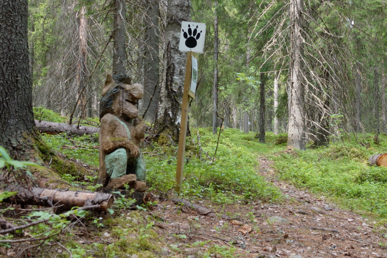 Puinen peikko istumassa luontopolun varrella.