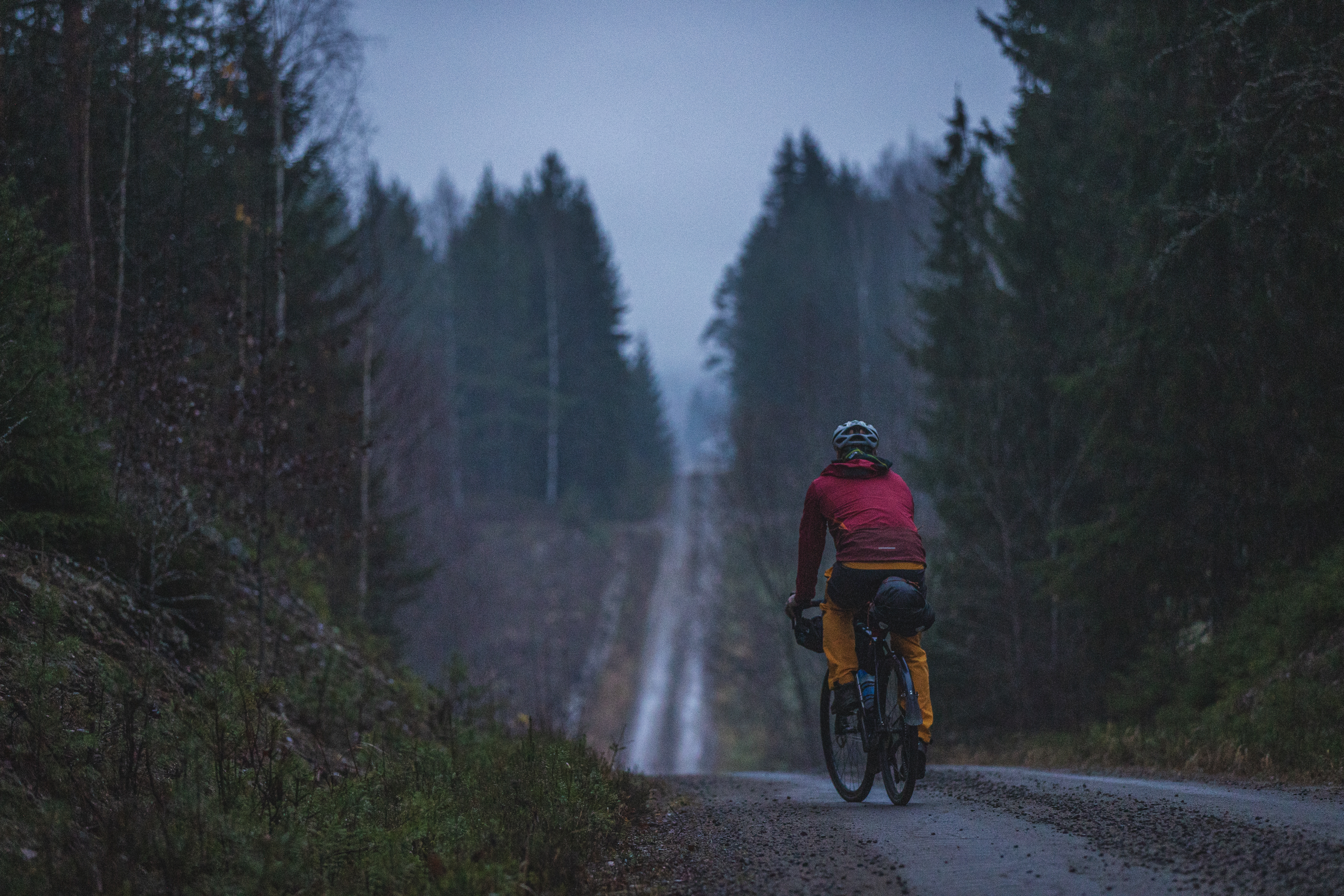 Mies pyörän kanssa mäen päällä. Hän katsoo alamäkeen jonka jälkeen alkaa uusi mäki.