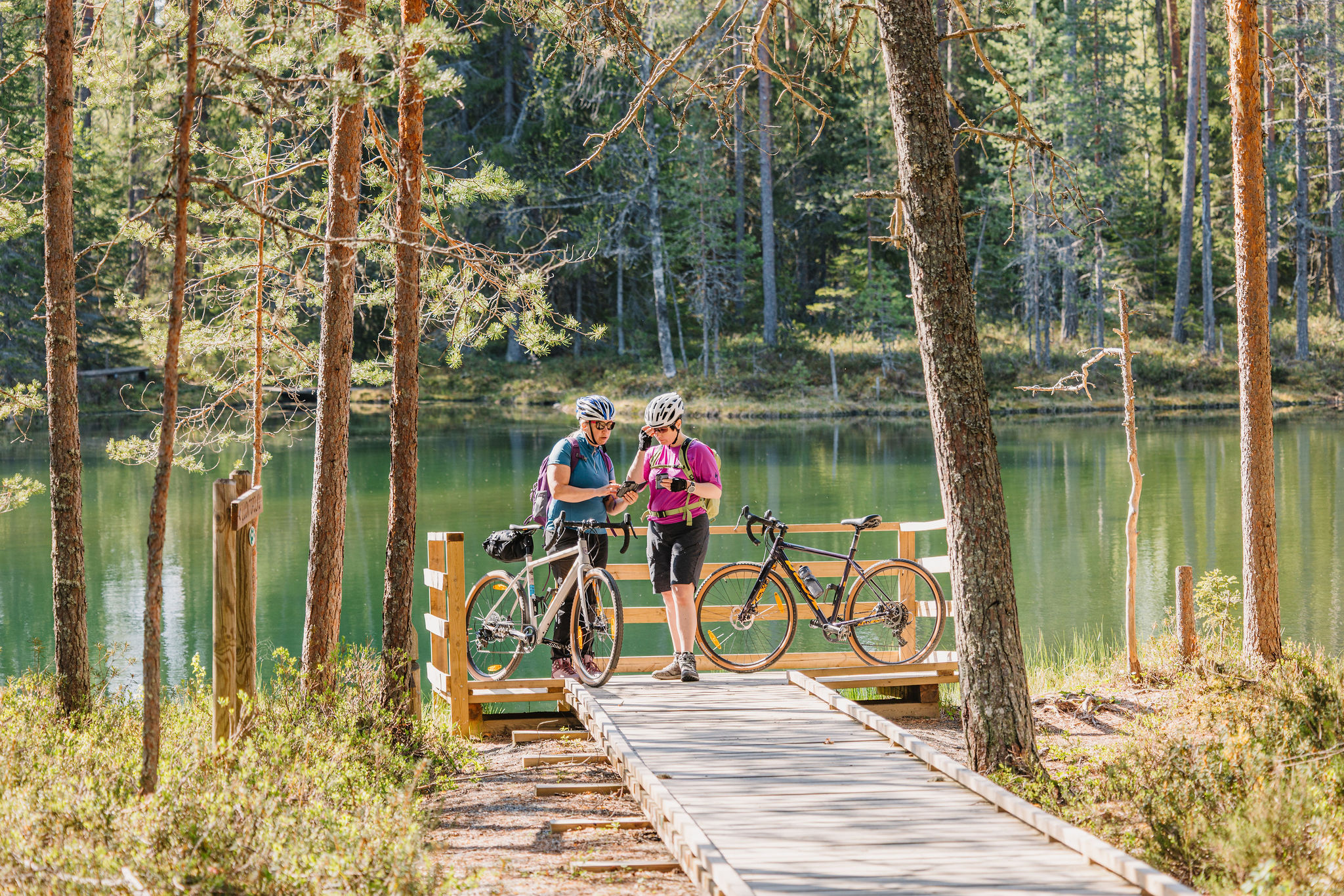 Two cyclists read a map at the end of an accessible boardwalk.