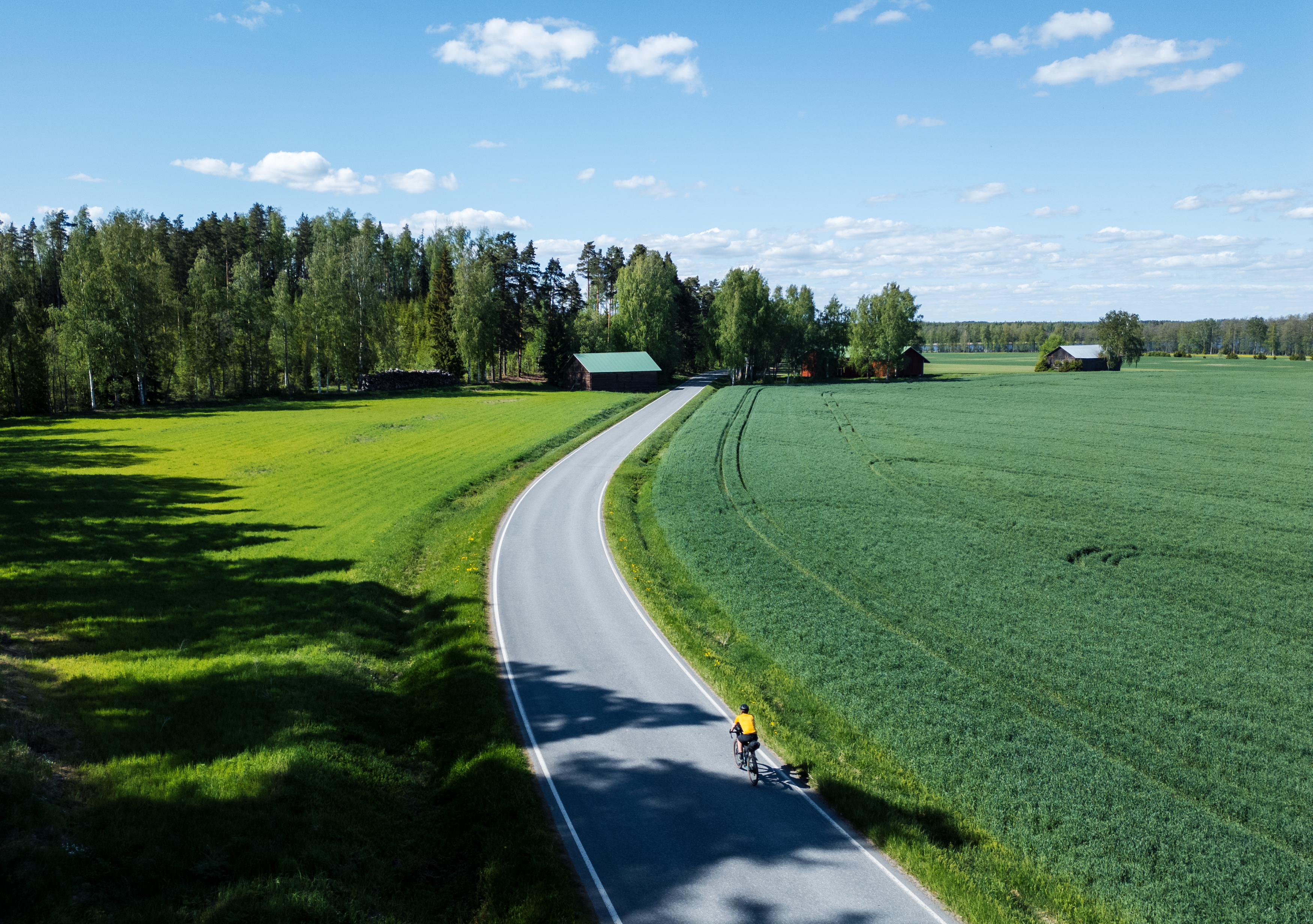 Pyöräilijä maaseutumaisemassa.