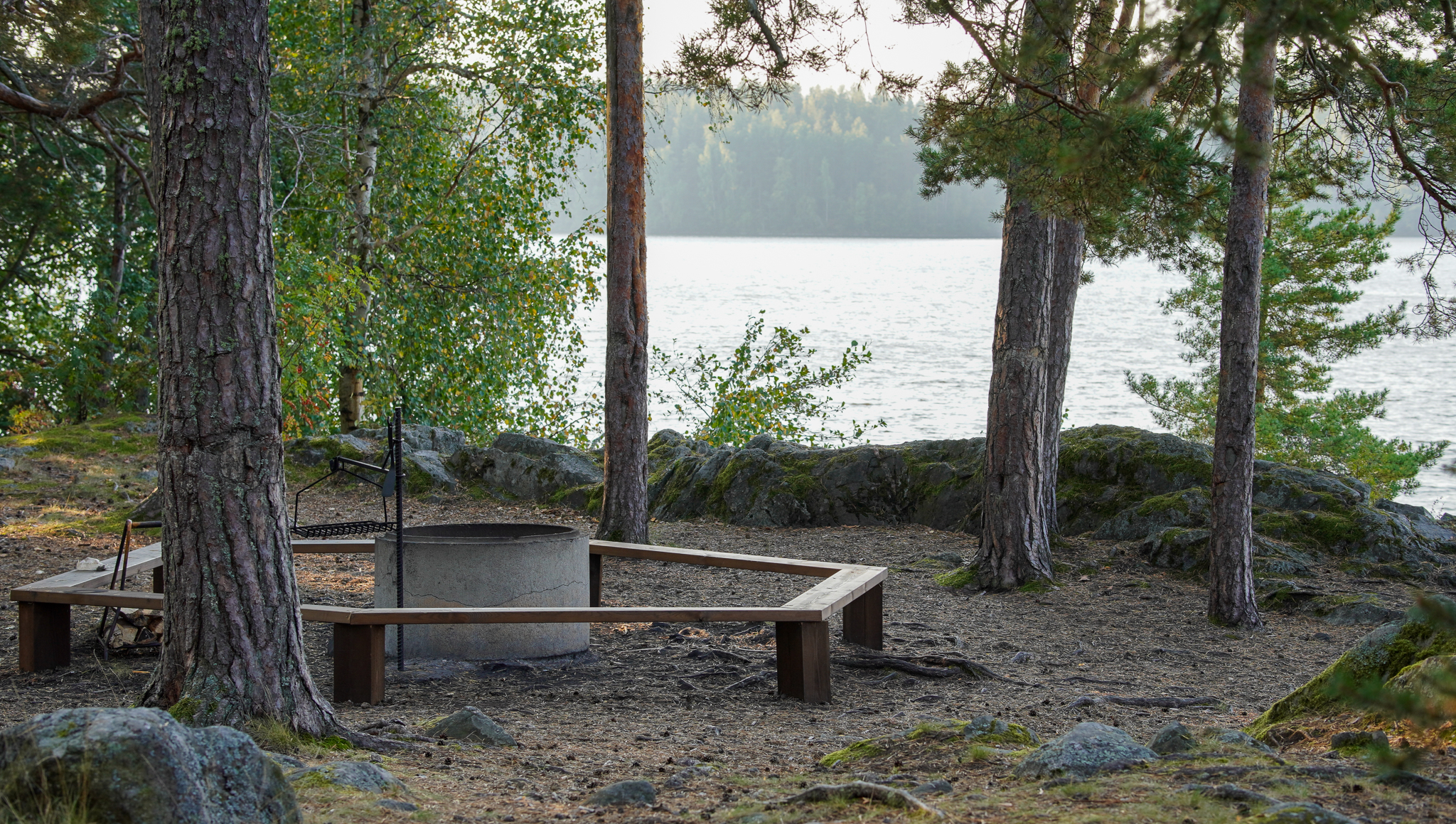 Metsäisellä kalliolla on betonirengas, jonka ympärillä on puiset penkit.