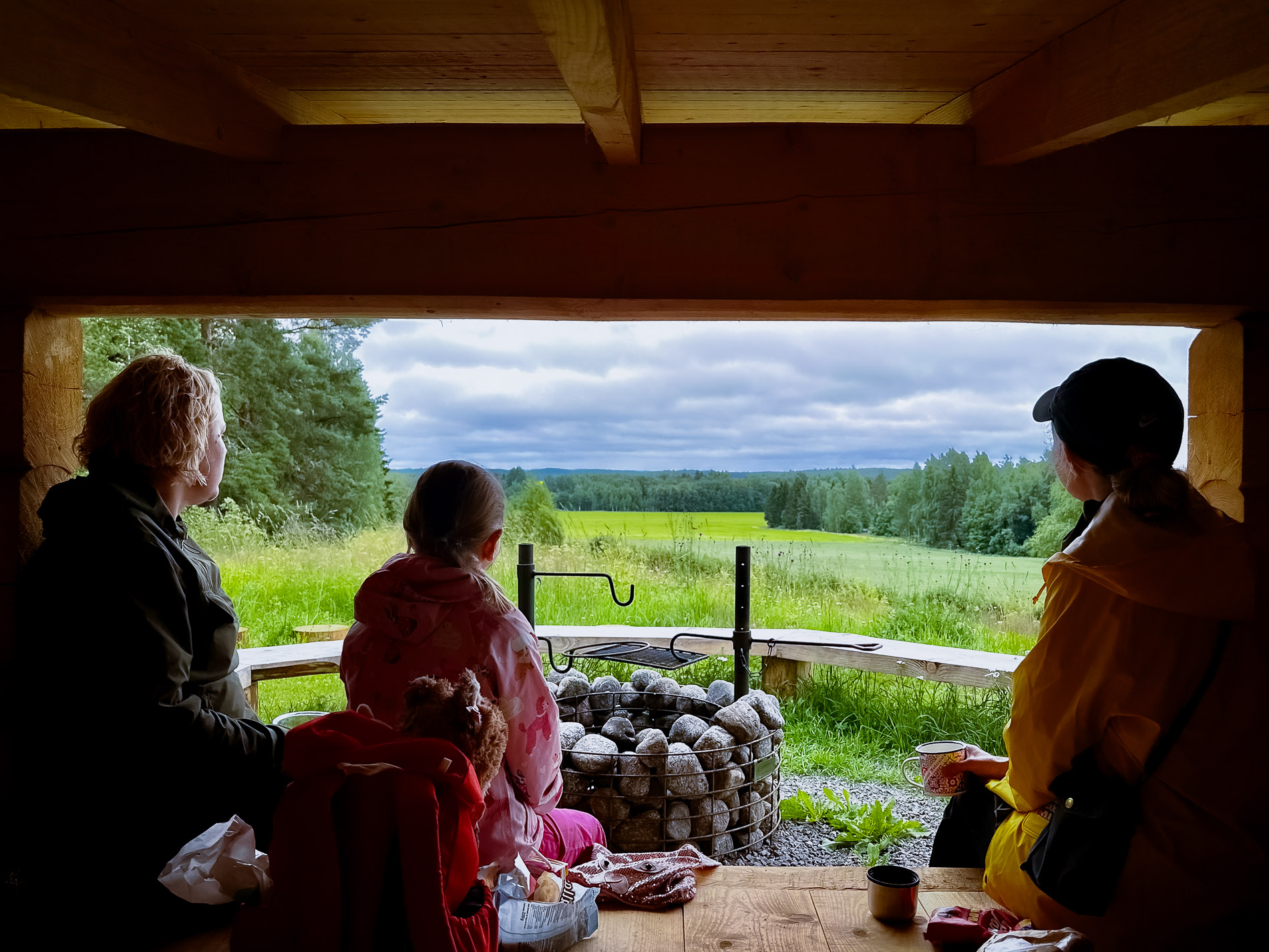 Two adults and a child are sitting on the shelter, looking out at the landscape.